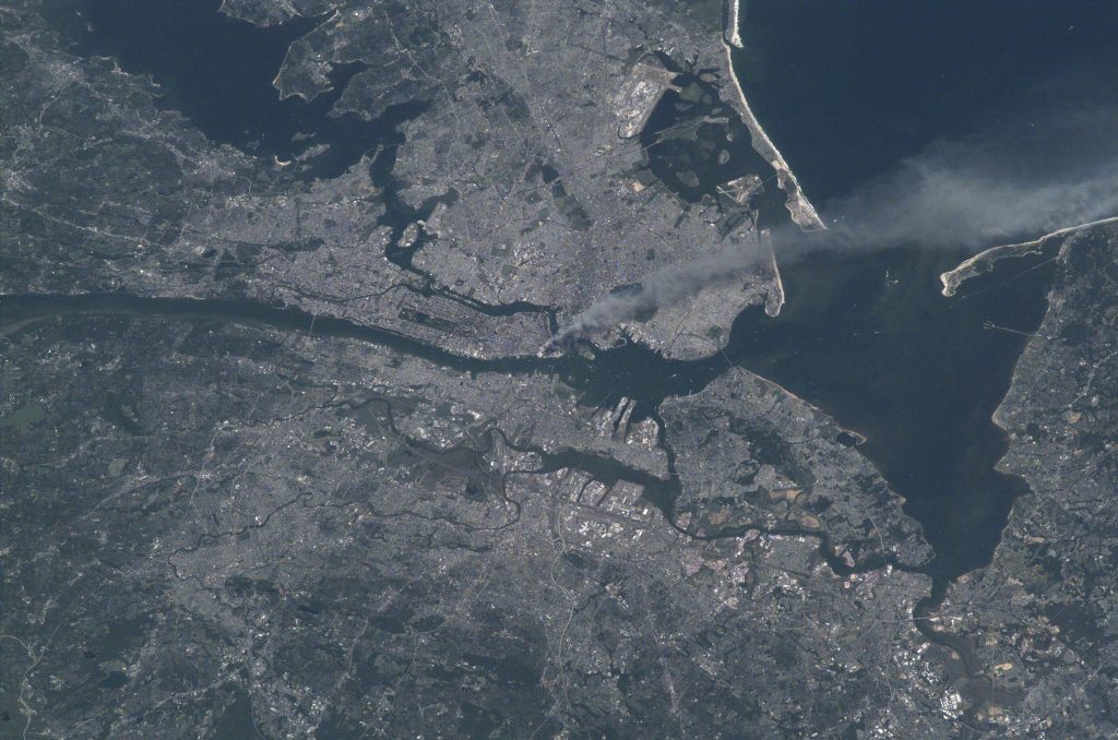 Visible from space, a smoke plume rises from the Manhattan area after two planes crashed into the towers of the World Trade Center. This photo was taken of metropolitan New York City (and other parts of New York as well as New Jersey) the morning of September 11, 2001. Credits: NASA